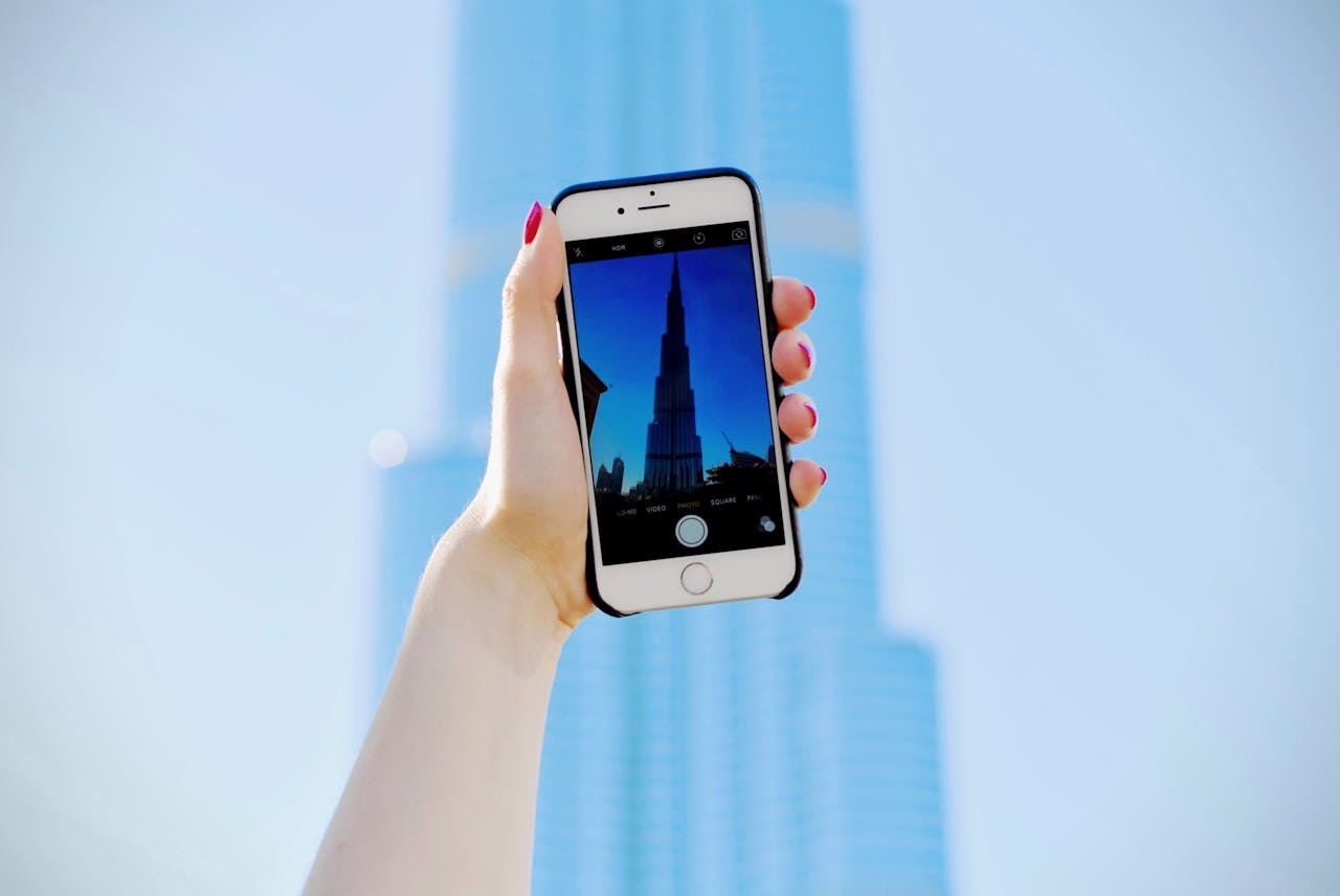 A hand holding a smartphone capturing the iconic Burj Khalifa in Dubai.